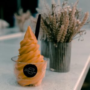 Delicious mango soft serve in a cup on a table with dried flowers. Perfect for summer treats.