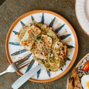 Top view of a healthy grilled halloumi and avocado sandwich on a decorative plate.