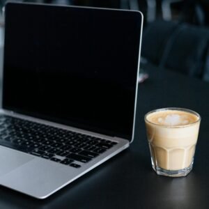 A sleek laptop and a latte on a dark tabletop, conveying modern work ambiance.